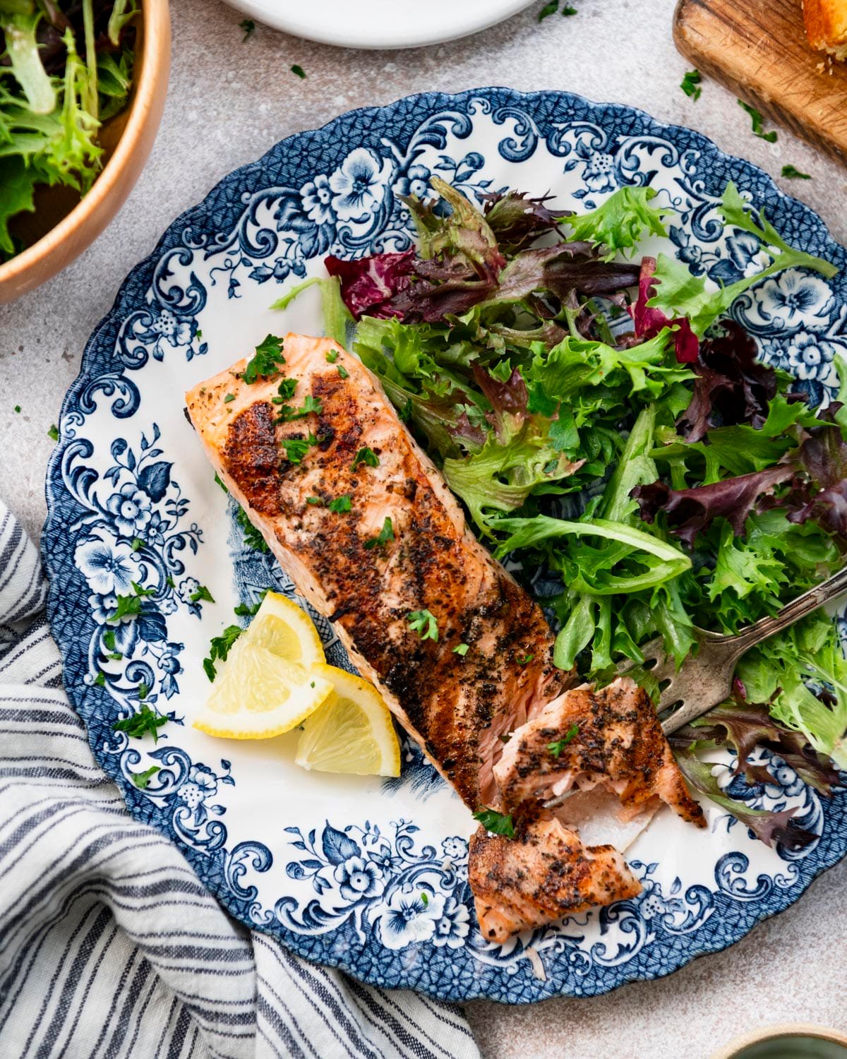 Close overhead image of the best grilled salmon recipe on a white table with a side salad and cornbread.