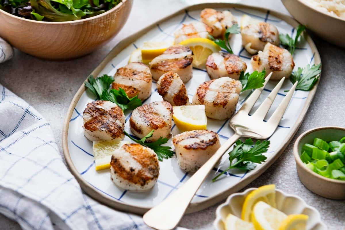 Horizontal side shot of grilled scallops on a tray.
