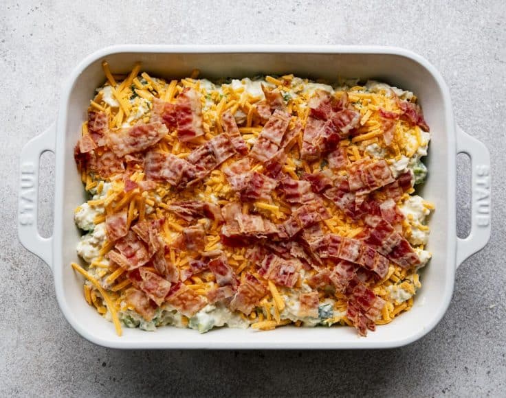 Jalapeno popper chicken casserole in a white dish before baking in the oven.