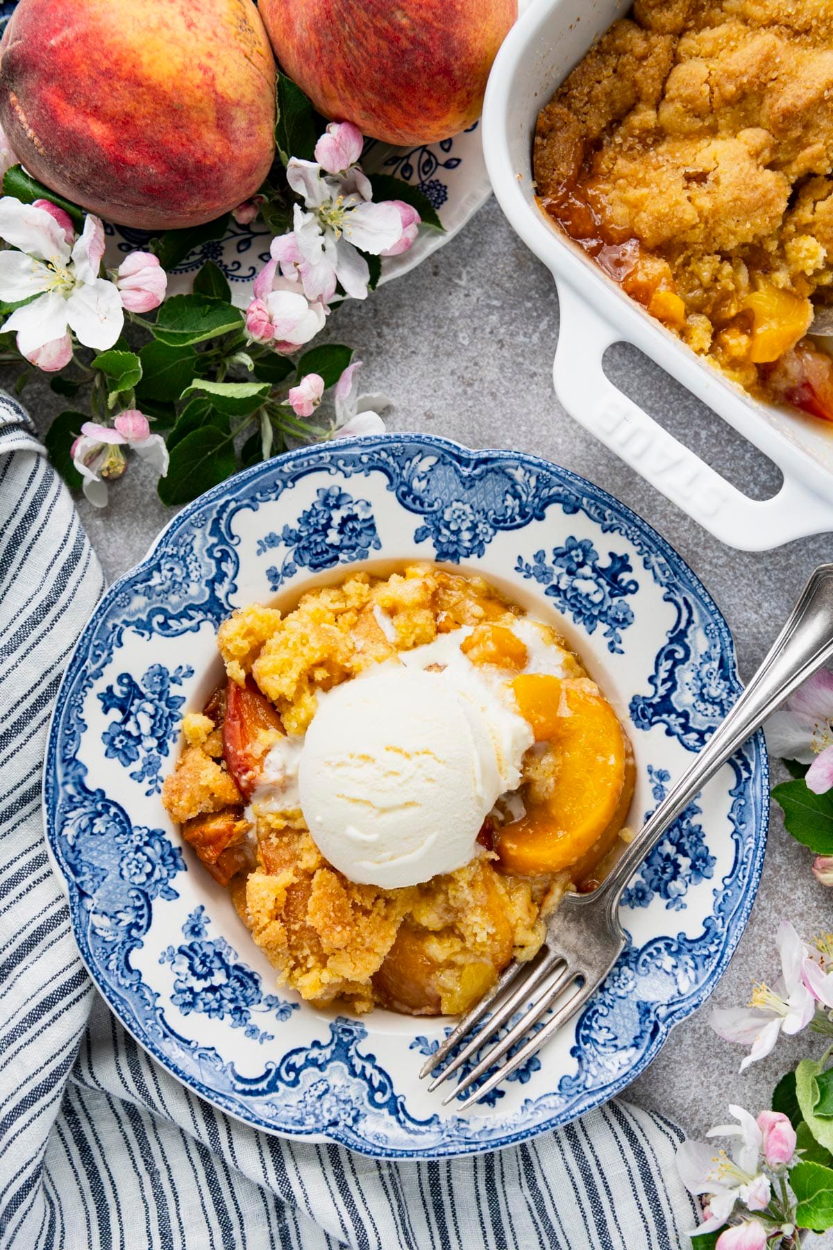 Overhead shot of southern peach cobbler with vanilla ice cream in a blue and white bowl.