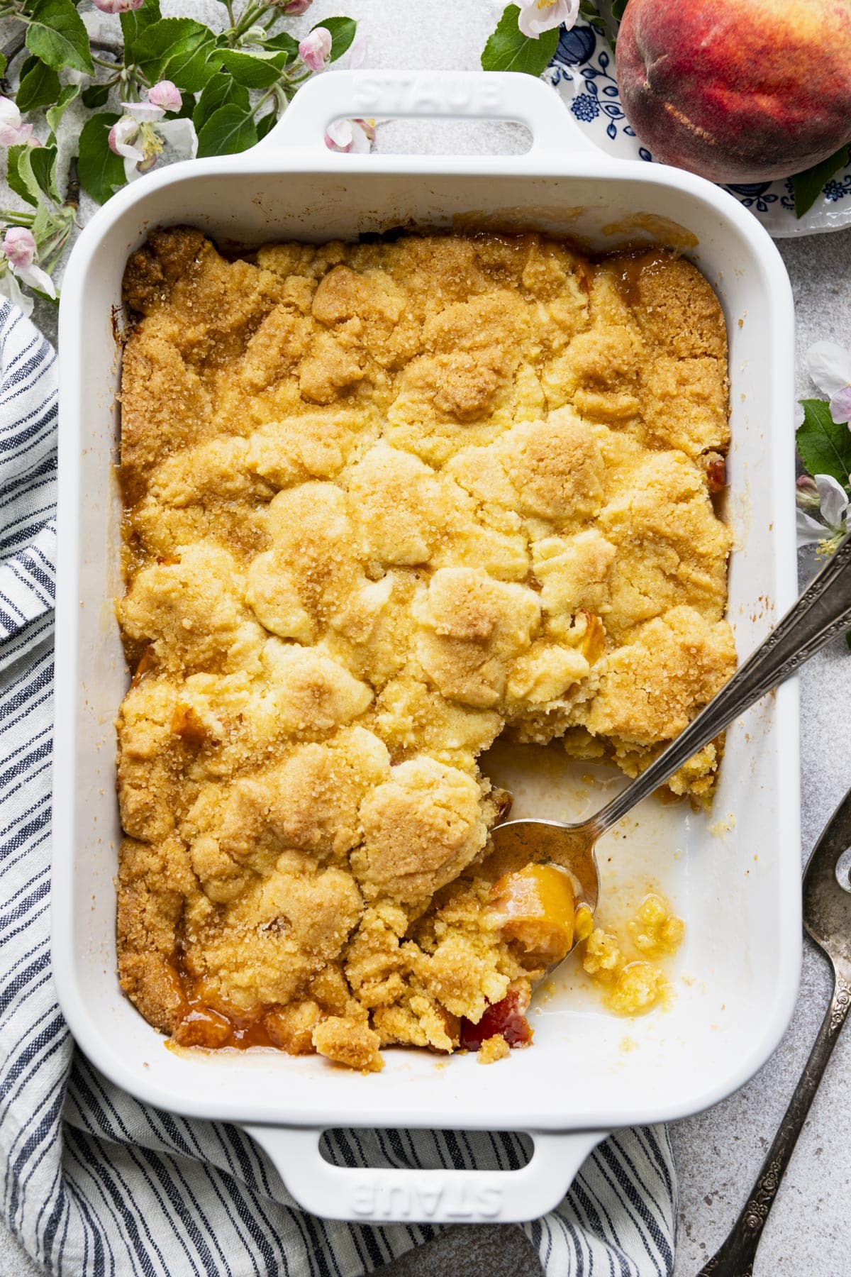 Easy peach cobbler with jiffy mix in a white baking dish.
