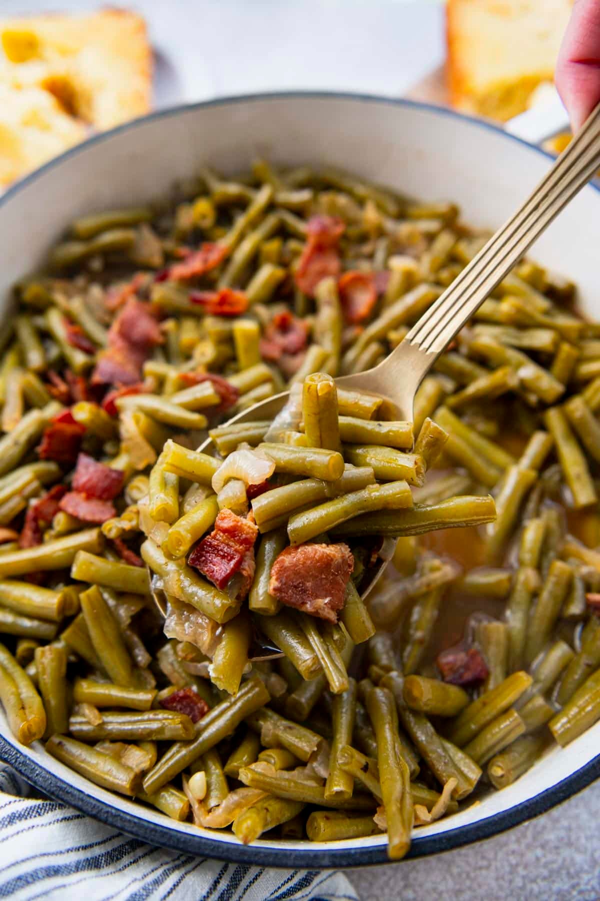 Close up side shot of a spoon serving southern style green beans.