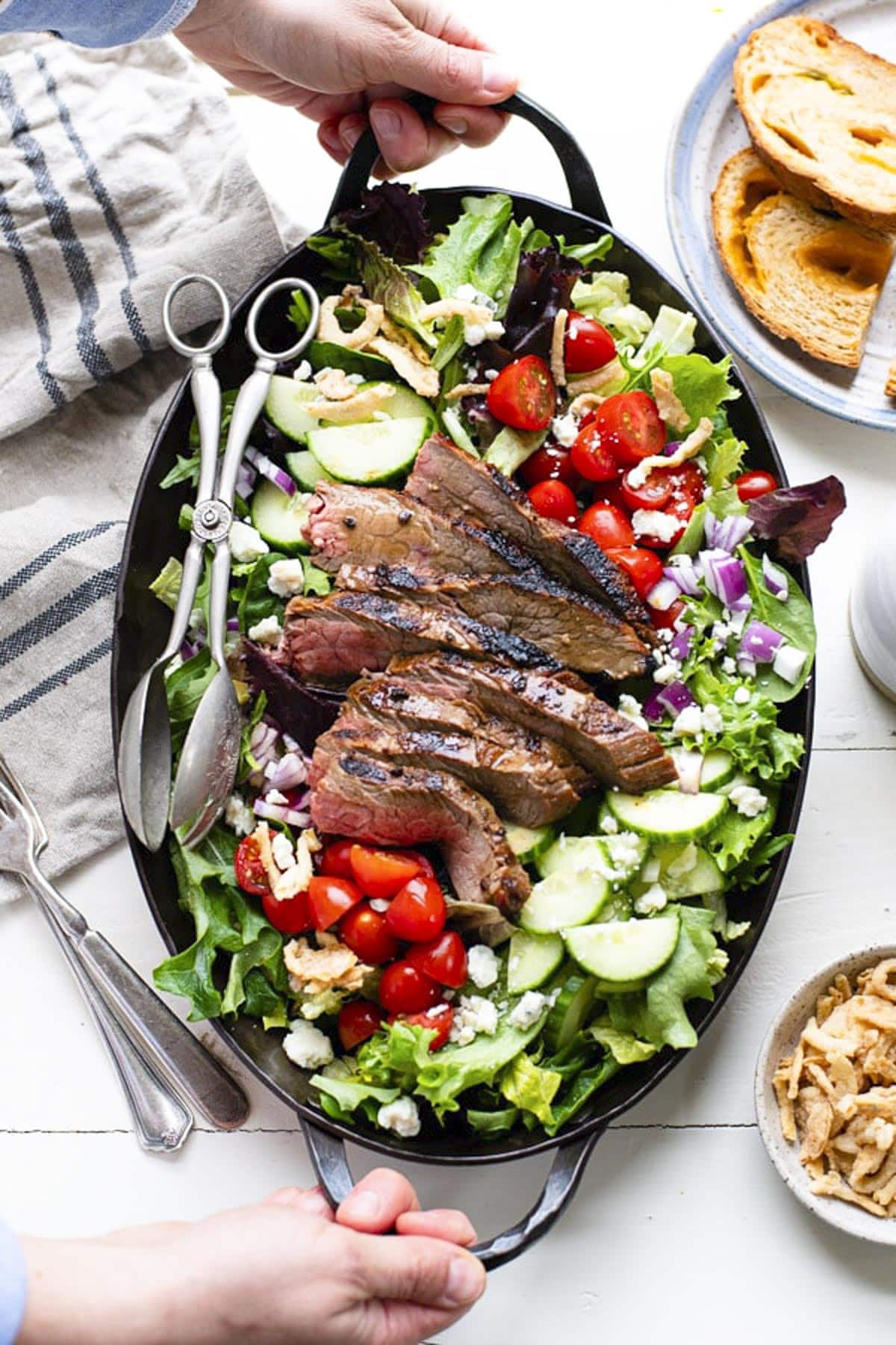 Simple steak salad with grilled flank steak and homemade balsamic dressing on a white table.