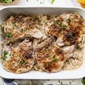 Horizontal overhead image of baked pork chops and rice in a white casserole dish.