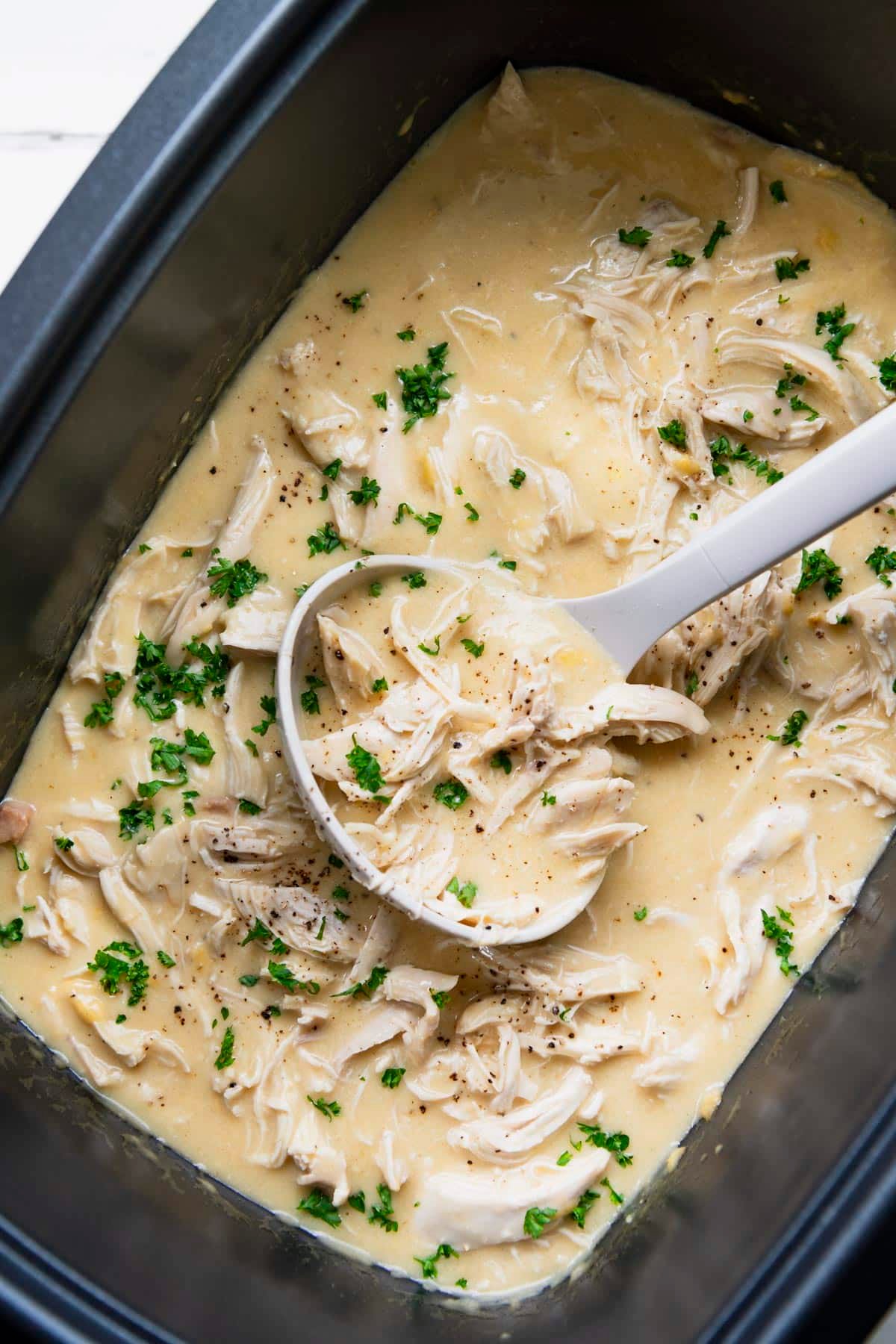 Vertical overhead shot of chicken and gravy in a slow cooker.