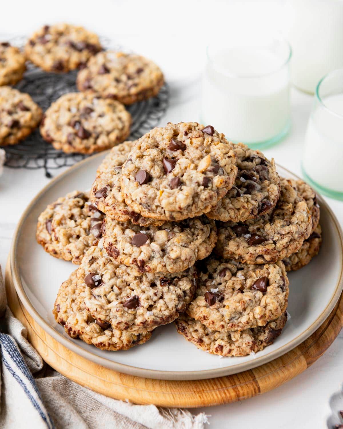 A plate of kitchen sink cookies on a white table with milk in the background.