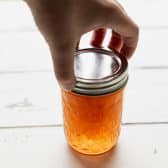 Tightening the lid on a jar of homemade peach jam.