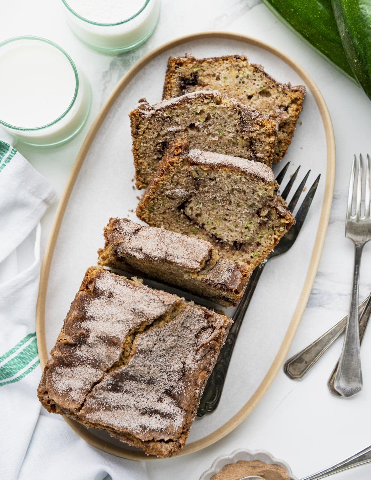 Overhead image of a white platter with a sliced loaf of cinnamon sugar zucchini bread.