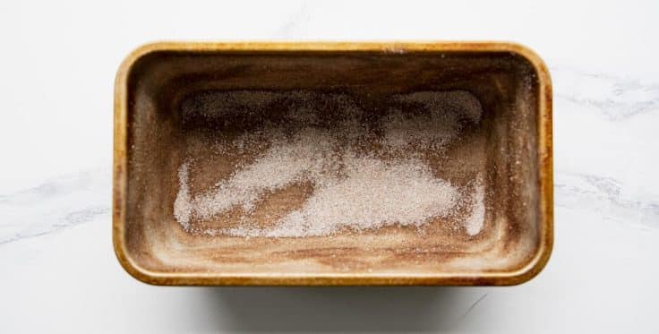 A loaf pan dusted with cinnamon sugar.