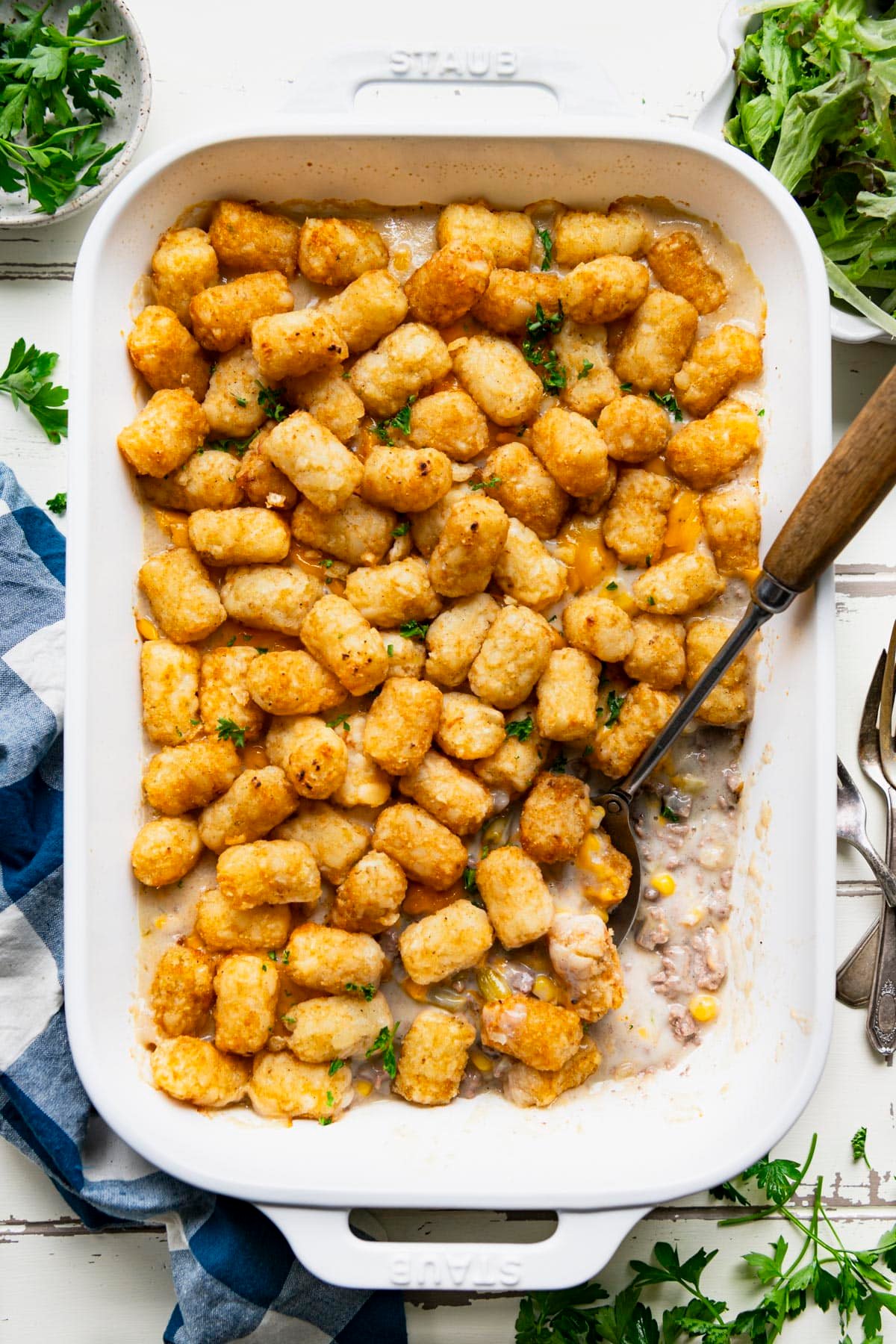 Overhead image of tater tot casserole with green beans on a white table.