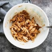Shredded rotisserie chicken tossed with bbq sauce in a bowl.