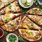 Horizontal overhead image of flatbread bbq chicken pizza sliced on a wooden cutting board.