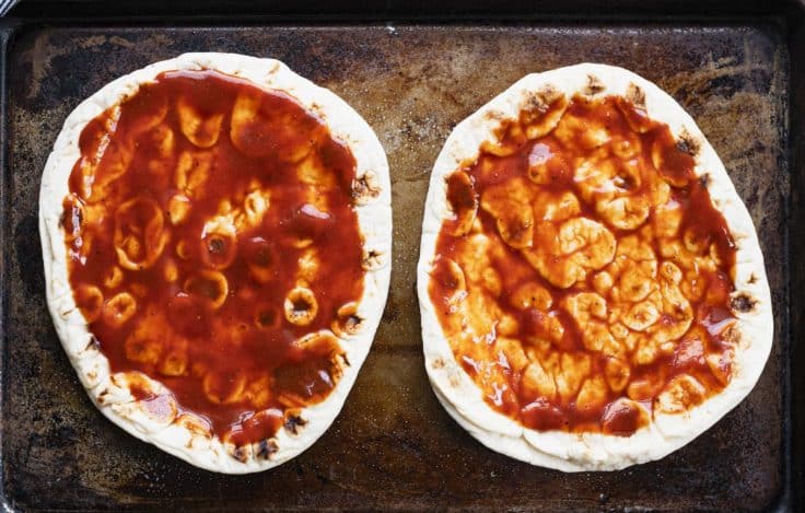 Barbecue sauce spread on two flatbreads.
