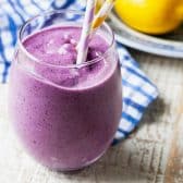 Horizontal shot of a banana blueberry smoothie on a white table.