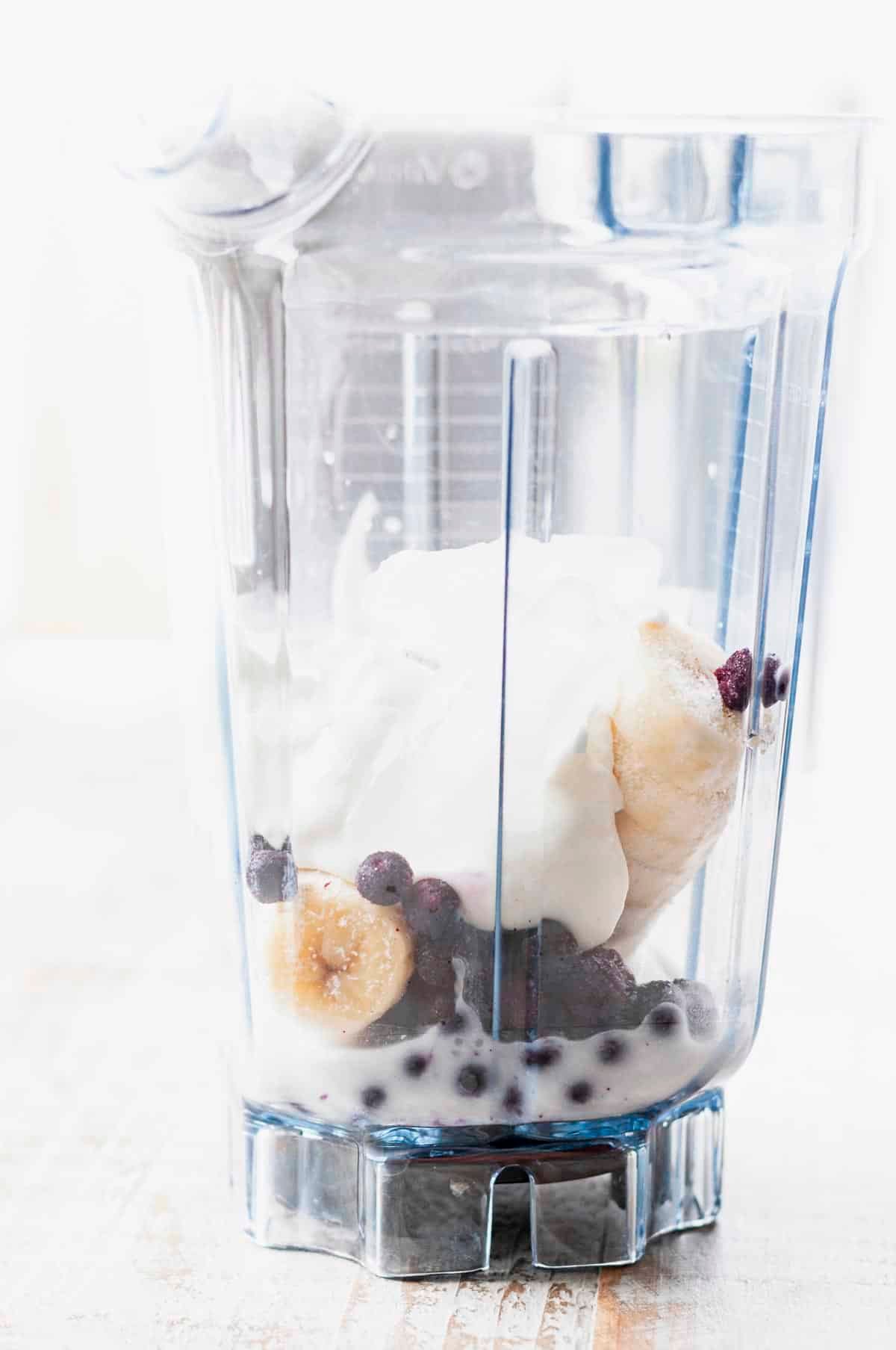 Ingredients for a blueberry banana smoothie in a blender.