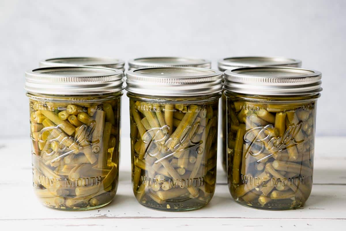 Horizontal image of jars showing how to can green beans.