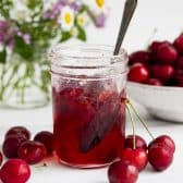 Square side shot of a jar of the best homemade cherry jam recipe.