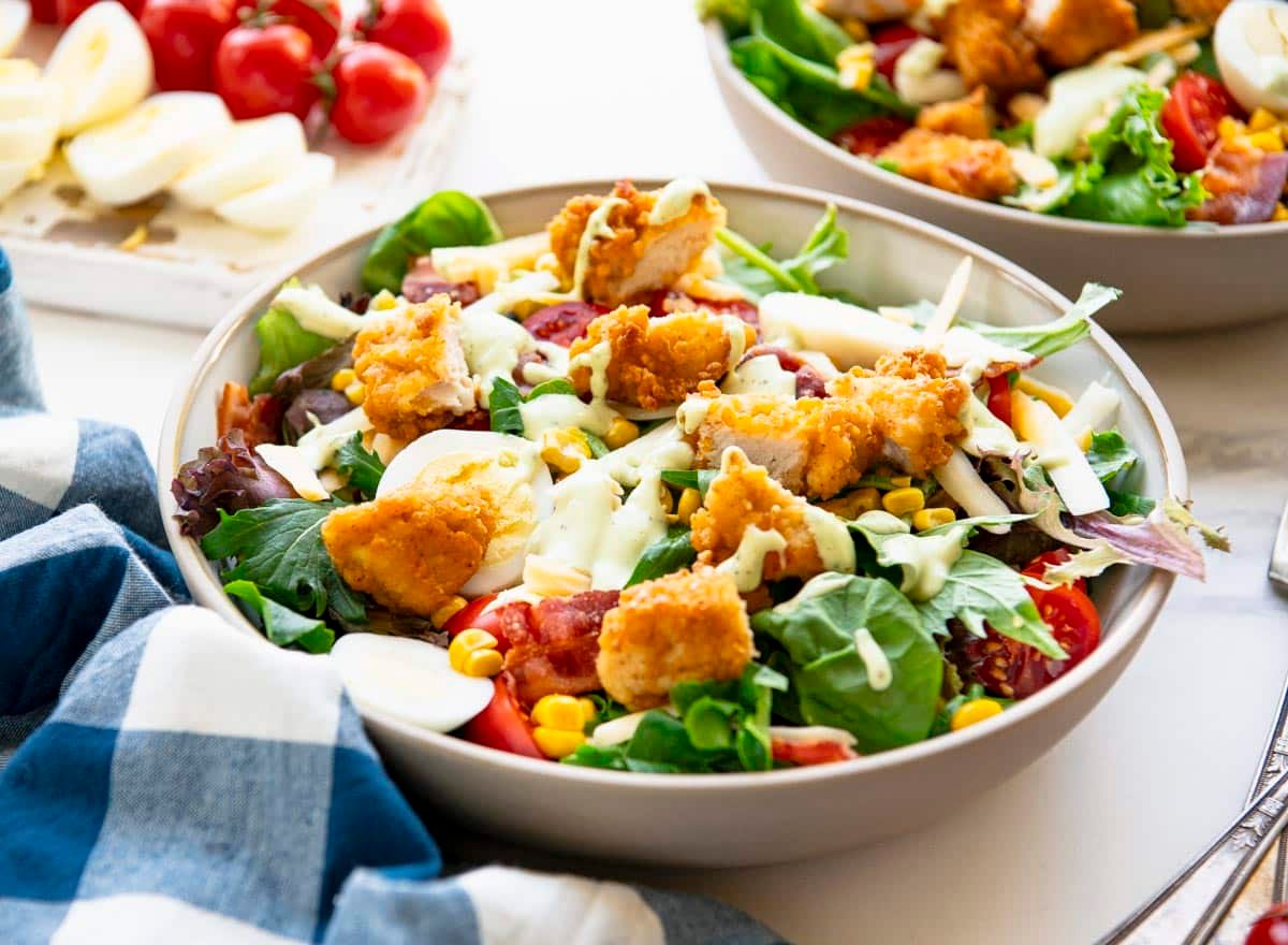 Horizontal side shot of a bowl of the best chick fil a cobb salad recipe on a white table.