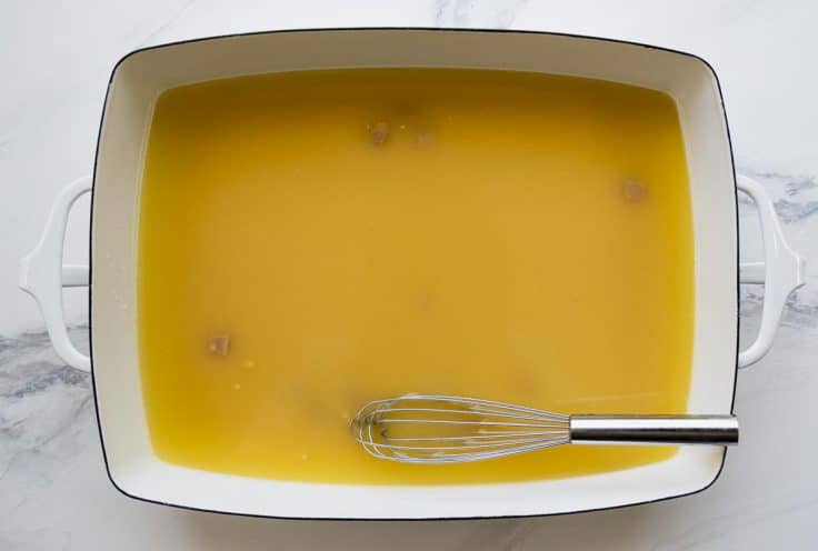 Whisking chicken broth and cream of chicken soup in a baking dish.