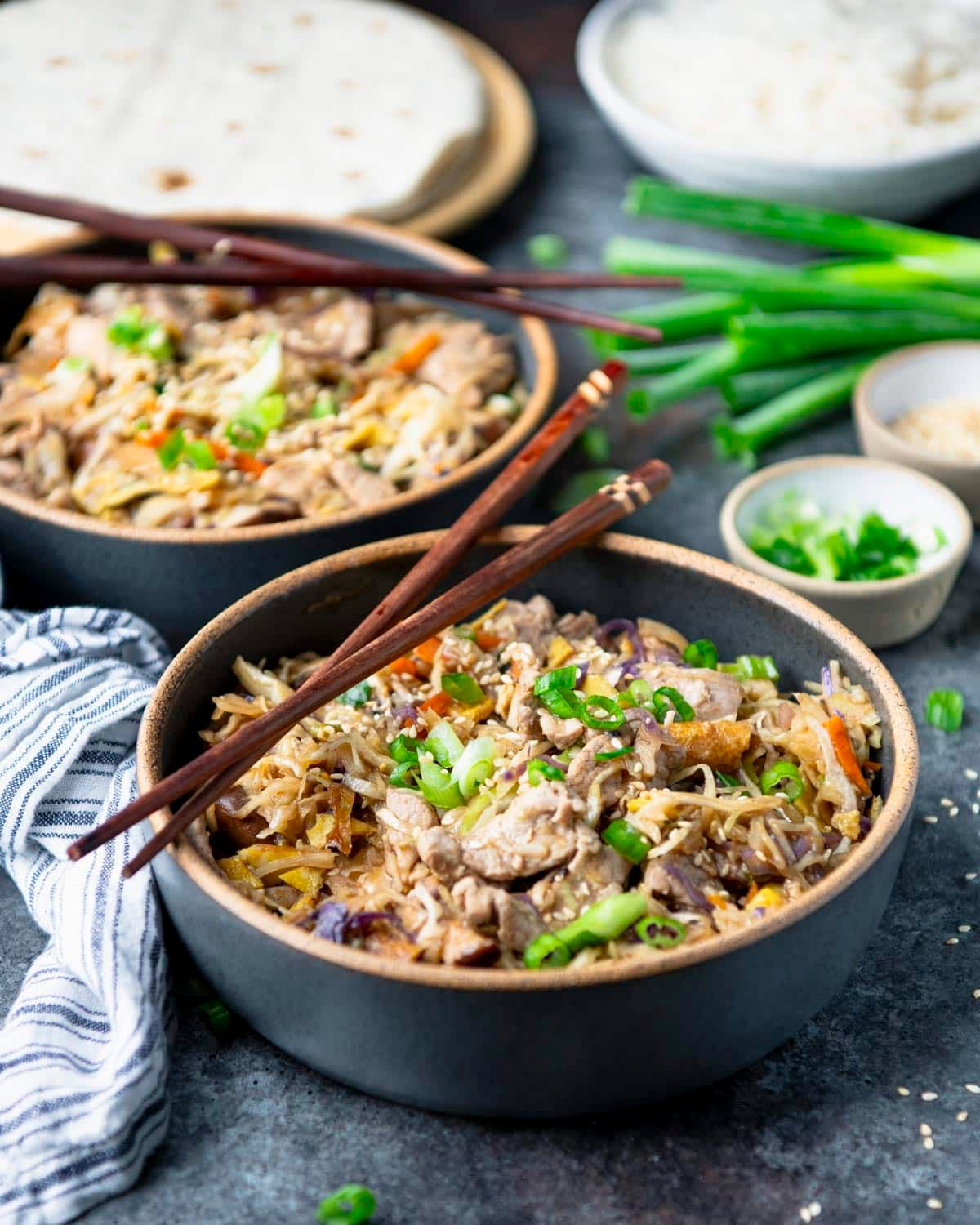 Easy homemade moo shu pork in bowls on a gray table.
