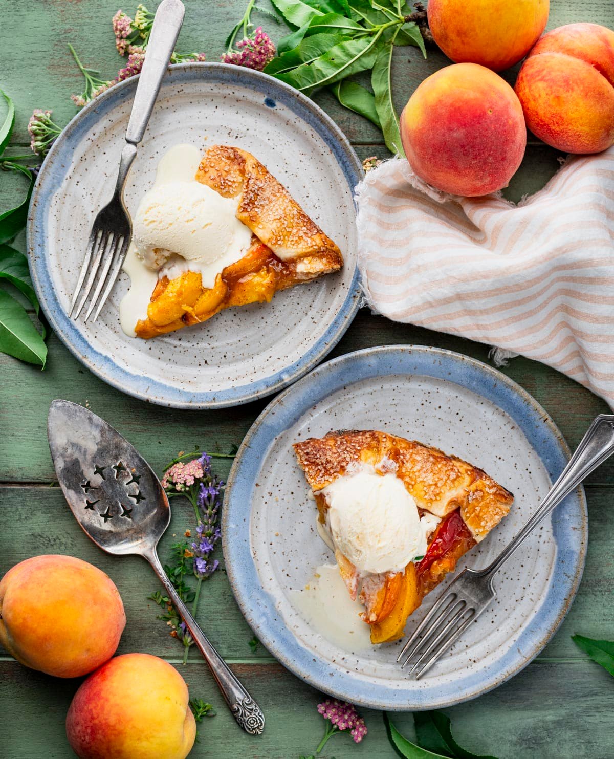 Overhead shot of slices of peach galette on plates with vanilla ice cream.