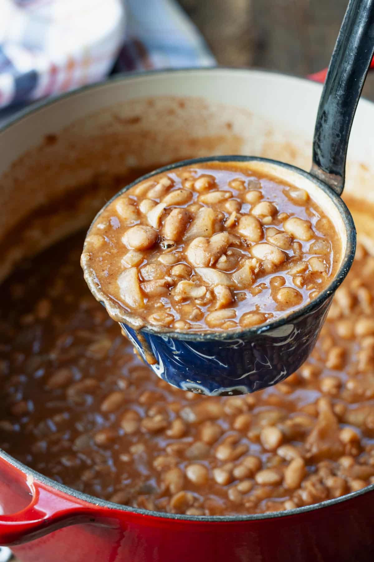 Side shot of homemade ranch style beans in a ladle.
