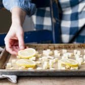 Arranging sliced lemons and diced butter on a sheet pan.