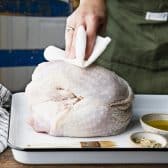 Patting a turkey breast dry with paper towels.