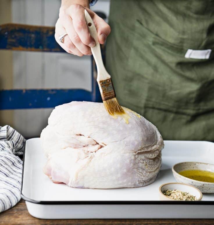 Brushing a turkey breast with oil.