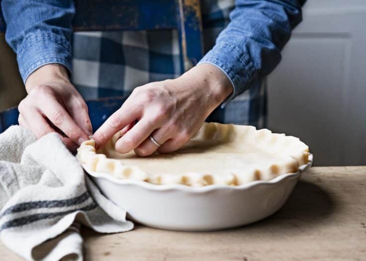Process shot showing how to crimp pie crust for chicken pot pie.