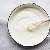 Whisking together white creamy sauce for casserole filling.