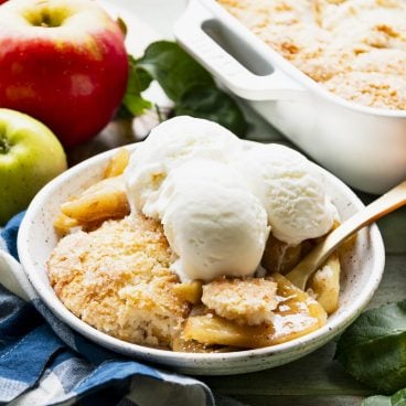 Close up square side shot of a bowl of the best apple cobbler recipe with ice cream on top.