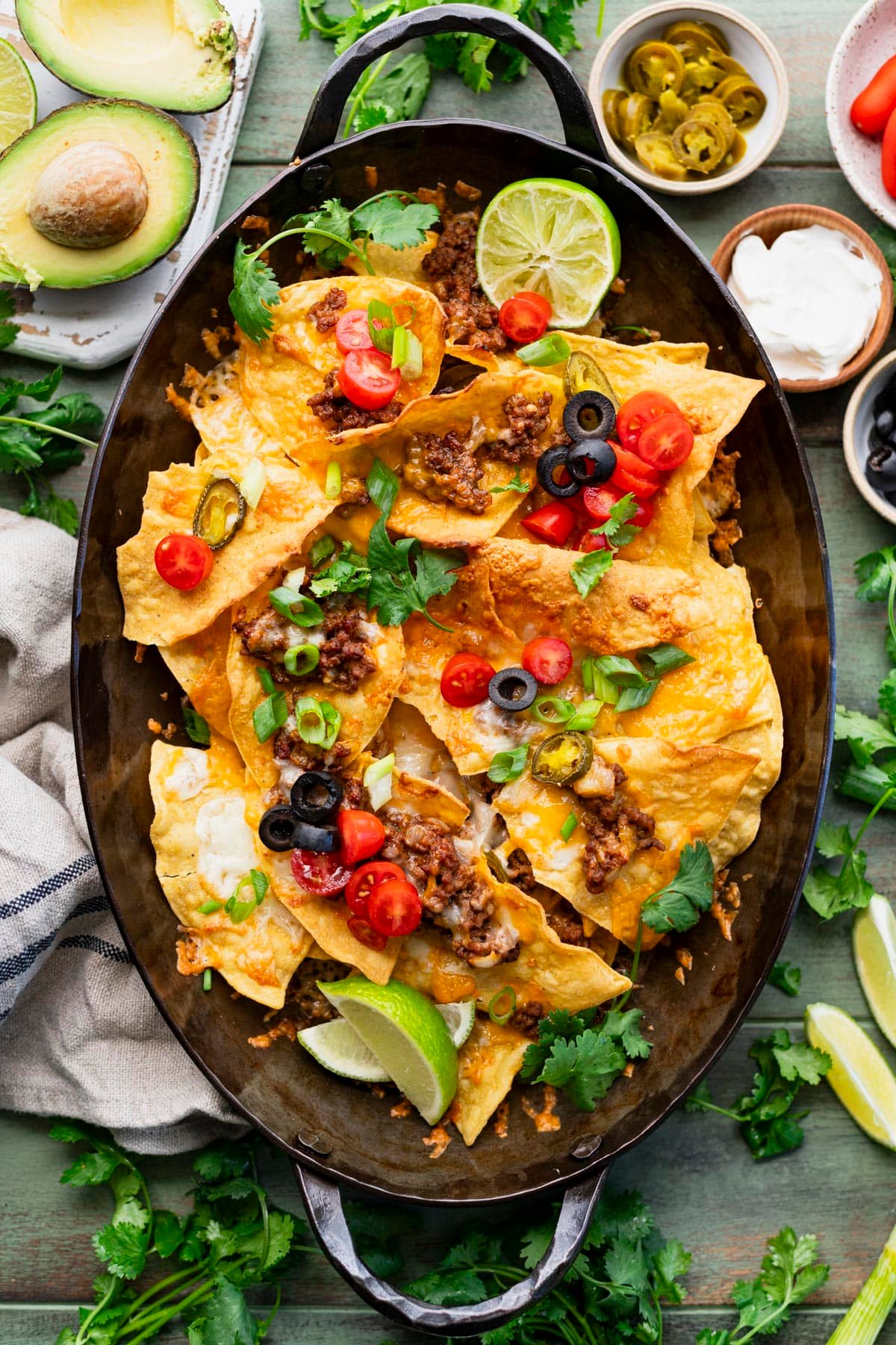 Overhead image of a cast iron tray full of the best homemade ground beef nachos recipe.