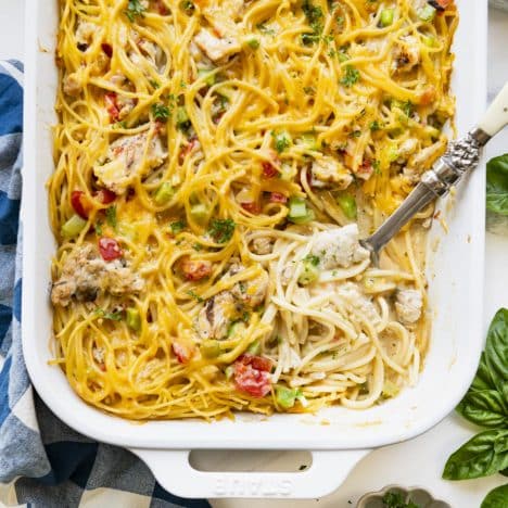 Square overhead image of chicken spaghetti casserole in a white baking dish.