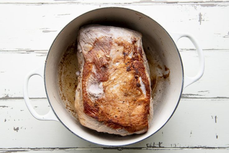 Browning a pork shoulder roast in a Dutch oven.