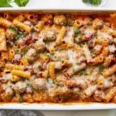 Close overhead image of a white baking dish full of dump and bake creamy tomato pasta with turkey meatballs.