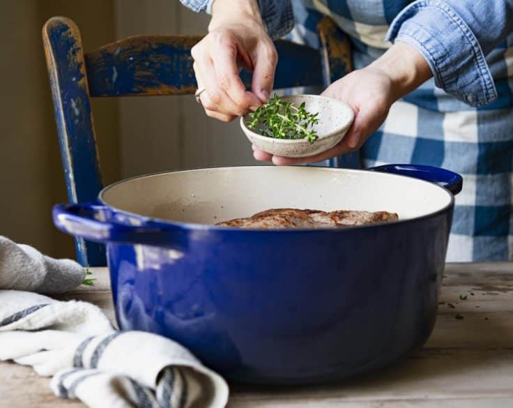 Adding herbs to a Dutch oven.
