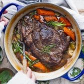 Square overhead image of hands serving a pot roast from a cast iron dutch oven.