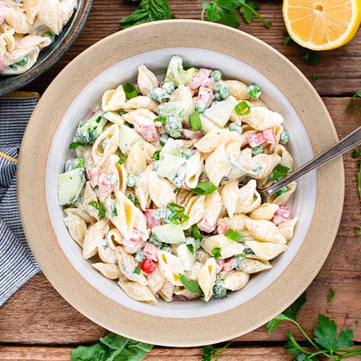 Square overhead shot of an easy pasta salad with mayo on a rustic wooden picnic table.