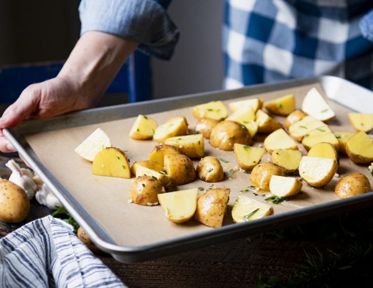 Process shot showing how to roast gold potatoes with rosemary and olive oil.