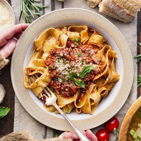 Square overhead shot of an easy Bolognese recipe served with pasta on a dinner table.