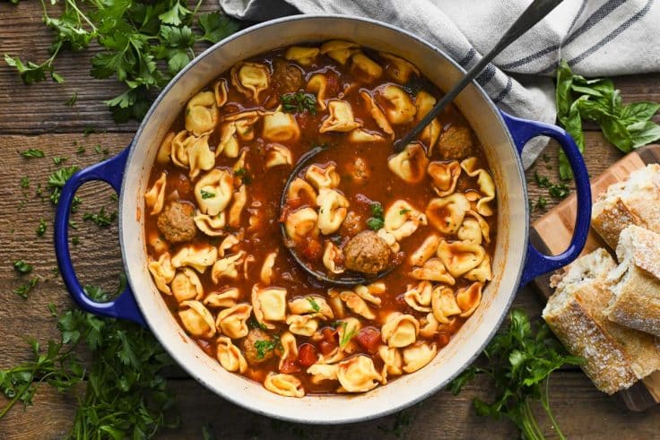 Ladle in a Dutch oven full of meatball tortellini soup.