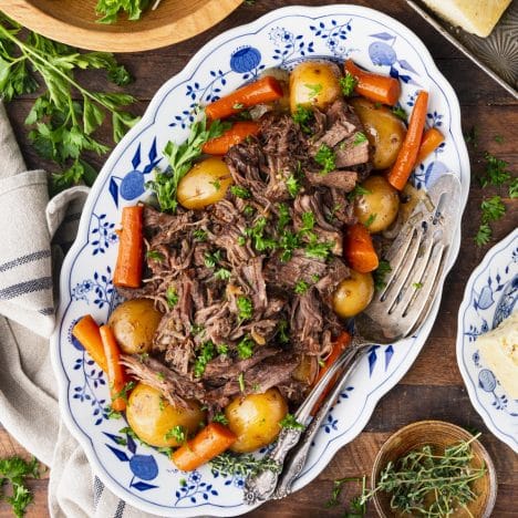 Square overhead shot of slow cooker pot roast with Coke on a blue and white serving tray.